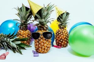 Un ananas portant des lunettes de soleil est entouré par des